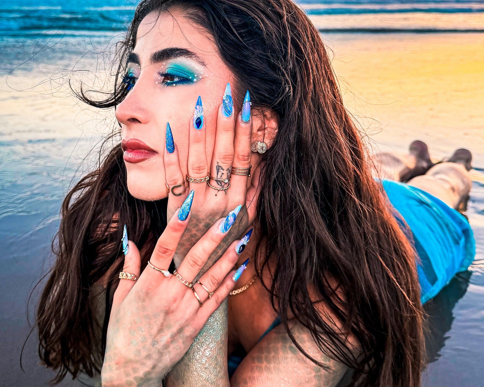 Model in mermaid makeup at golden hour wearing The Lost Kingdom blue stiletto press-on nails from Summer in Atlantis