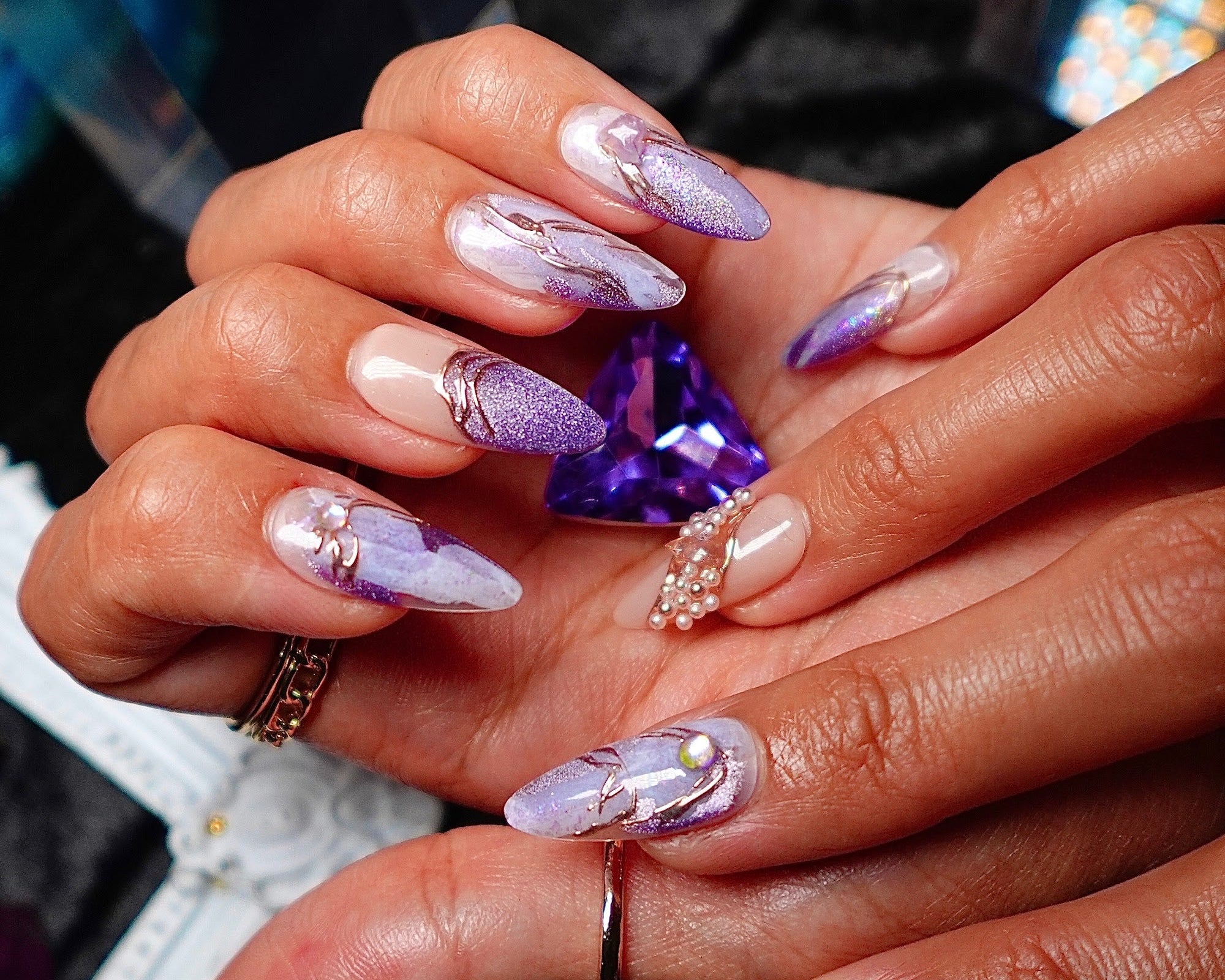 Hands holding a cut amethyst, wearing Amethyst lilac marble press-on nails from Crystal Muse