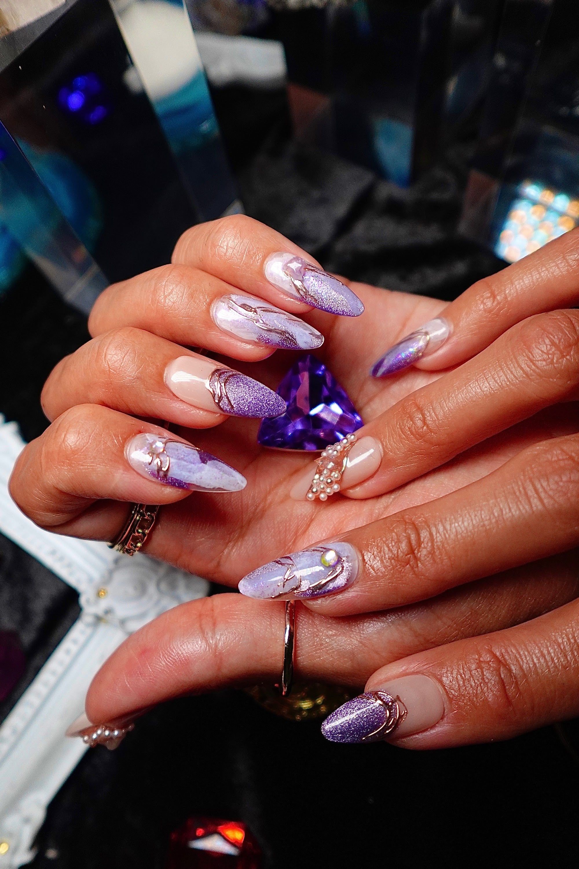 Hands holding a cut amethyst, wearing Amethyst lilac marble press-on nails from Crystal Muse