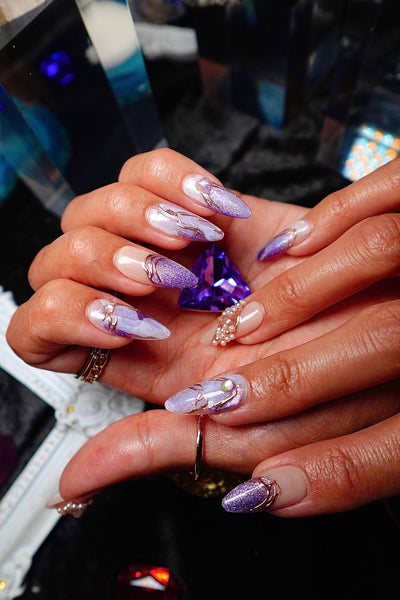 Hands holding a cut amethyst, wearing Amethyst lilac marble press-on nails from Crystal Muse